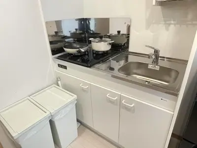 a kitchen with a sink and a stove with pots and pans at COMMA HOUSE Kitaikebukuro 203 in Tokyo