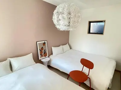 a room with two beds and a chair and a chandelier at COMMA HOUSE Kitaikebukuro 203 in Tokyo