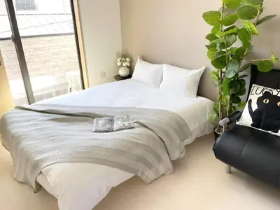 a bedroom with a large white bed and a plant at COMMA HOUSE Kitaikebukuro 301 in Tokyo