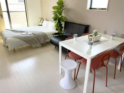 a bedroom with a bed and a white table and chairs at COMMA HOUSE Kitaikebukuro 301 in Tokyo