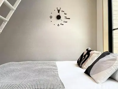 a bedroom with a bed with a clock on the wall at COMMA HOUSE Kitaikebukuro 302 in Tokyo