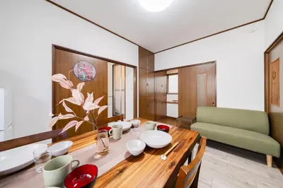 a dining room with a table and a green couch at 4-chome House Senju 2F - Cozy Japanese-Style Apartment, 8 min to Kita-Senju in Tokyo