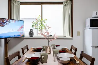 a dining room table with chairs and a television at 4-chome House Senju 2F - Cozy Japanese-Style Apartment, 8 min to Kita-Senju in Tokyo