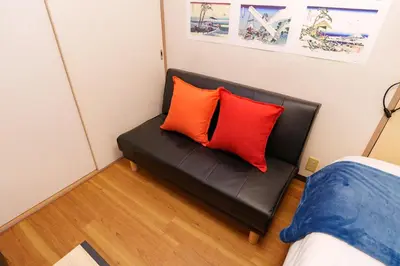 a black couch in a room with two red pillows at \u30aa\u30fc\u30d7\u30f3\u7279\u4fa1 \u5317\u658e \u5bcc\u58eb\u306e\u9593 \u6c60\u888b4\u5206 \u65b0\u5bbf16\u5206 \u6e0b\u8c3721\u5206 in Tokyo