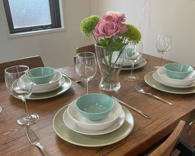 a wooden table with plates and bowls and a vase of flowers at Iwamoto compound 301 \u5ca9\u672c\u30b3\u30f3\u30d1\u30a6\u30f3\u30c9301 in Tokyo