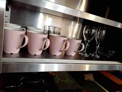 a row of coffee mugs and wine glasses on a shelf at Pro Kitchen and Karaoke 100sqm amusement hotel in Tokyo