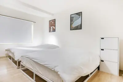 a white bedroom with a bed and a window at \u99c5\u304b\u3089\u5f92\u6b691\u5206 \u5de3\u9d28\u99c5 \u6700\u59274\u540d \u7121\u6599wifi 45\u5e73\u7c73\u3067\u5e83\u3044\u304a\u90e8\u5c4b in Tokyo