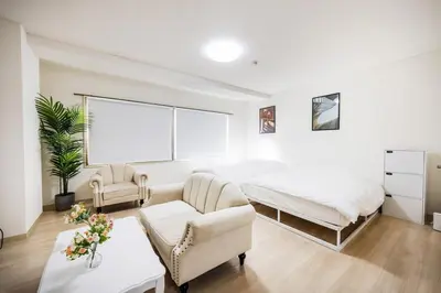 a white bedroom with a bed and a couch at \u99c5\u304b\u3089\u5f92\u6b691\u5206 \u5de3\u9d28\u99c5 \u6700\u59274\u540d \u7121\u6599wifi 45\u5e73\u7c73\u3067\u5e83\u3044\u304a\u90e8\u5c4b in Tokyo