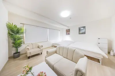 a white bedroom with a bed and a couch at \u99c5\u304b\u3089\u5f92\u6b691\u5206 \u5de3\u9d28\u99c5 \u6700\u59274\u540d \u7121\u6599wifi 45\u5e73\u7c73\u3067\u5e83\u3044\u304a\u90e8\u5c4b in Tokyo