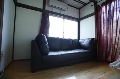 a couch in a living room with a large window at Yanesen Traditional Nagaya house in Tokyo