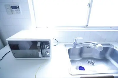 a kitchen sink with a microwave next to it at Yanesen Traditional Nagaya house in Tokyo