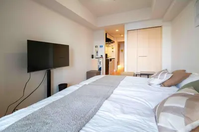a bedroom with a large white bed with a flat screen tv at FIKA Higashi Shinjuku in Tokyo