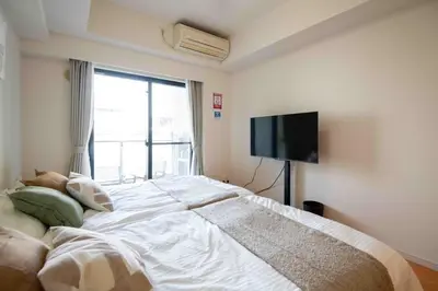 a bedroom with a large bed with a flat screen tv at FIKA Higashi Shinjuku in Tokyo