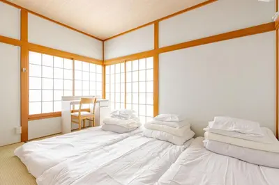 a large white bed in a room with windows at Fukurou House in Tokyo