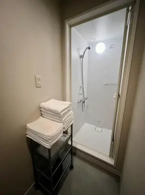a bathroom with a shower and a stack of towels at KILN-torigoe2chome INN in Tokyo
