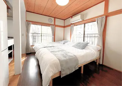 a bedroom with a large bed and two windows at Asakusa Sky House in Tokyo