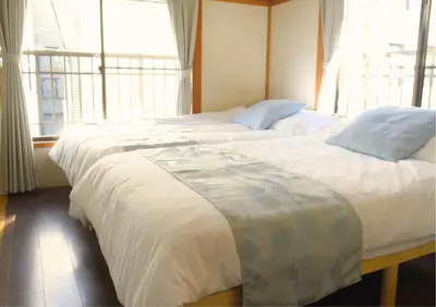 two beds in a room with two large windows at Asakusa Sky House in Tokyo