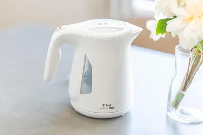a white electric kettle sitting next to a vase of flowers at \u6b74\u53f2\u7684\u5bfa\u9662\u8fd1\u304f \u89b3\u5149\u5730\u3078\u306e\u30a2\u30af\u30bb\u30b9\u4fbf\u5229 Qe in Tokyo