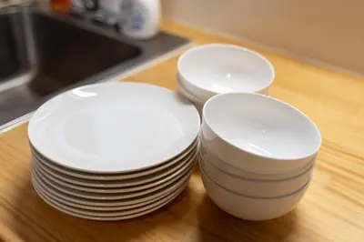 three stacks of white plates sitting on a table at \u697d\u9038\u30b0\u30eb\u30fc\u30d7 \u56db\u30c4\u6728 102t in Tokyo
