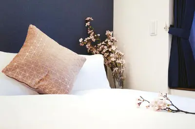 a bed with a pillow and a vase of flowers at \u90fd\u5fc3\u7f55\u89c1 \u79cb\u53f6\u539f\u4e1c\u4eac\u7ad9KDoa \u8d85\u7ea7\u5962\u534e\u53cc\u5367\u5957\u623f\u5e26\u53a8\u623f \u5730\u94c13\u5206\u949f \u6234\u68eePOLA\u9876\u7ea7\u914d\u7f6e \u79cb\u53f6\u539f\u6b65\u884c\u53ef\u8fbe \u4e1c\u4eac\u7ad94\u5206\u949f in Tokyo