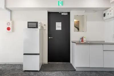 a kitchen with a black door and a white refrigerator at \u6771\u4eac\u30bf\u30ef\u30fc\u8fd1 \u864e\u30ce\u9580\u30d2\u30eb\u30ba\u99c5\u5f92\u6b694\u5206\u30b9\u30bf\u30a4\u30ea\u30c3\u30b7\u30e5 501 in Tokyo