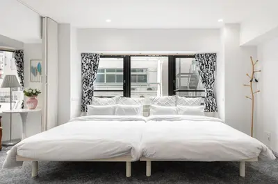 a white bedroom with a large bed with white pillows at \u6771\u4eac\u30bf\u30ef\u30fc\u8fd1 \u864e\u30ce\u9580\u30d2\u30eb\u30ba\u99c5\u5f92\u6b694\u5206\u30b9\u30bf\u30a4\u30ea\u30c3\u30b7\u30e5 501 in Tokyo