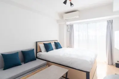 a bedroom with a bed with blue pillows and a couch at \u30ec\u30b8\u30c7\u30a3\u30a2\u4e2d\u843d\u5408b in Tokyo