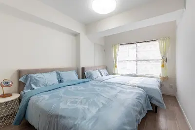 a bedroom with a bed with blue sheets and a window at \u4e0a\u91ce402 MAX 8 \u9280\u5ea7Asakusa\u30a8\u30ea\u30a2Wi - Fi in Tokyo