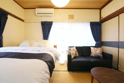 a bedroom with two beds and a couch and a window at \u6b63\u6804\u30cf\u30a4\u30c4101 in Tokyo