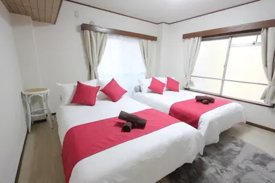 two beds in a room with red and white pillows at Hotel LUANA in Shin-Nakano in Tokyo