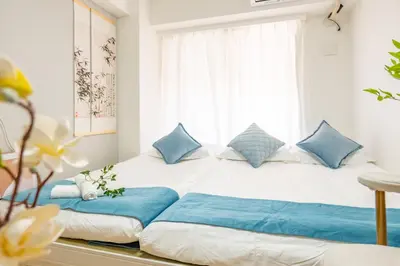 a bed with blue pillows in a room with a window at 3-person mansion in Shinjuku Kabukicho train 8 mins in Tokyo