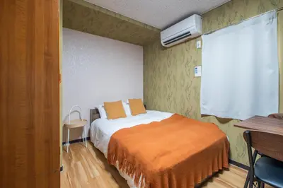 a bedroom with a bed with an orange blanket at \u96c0\u8272\u65b9\u5357 \u65b0\u5bbf\u99c5\u307e\u306714\u5206 \u6771\u4eac\u99c5\u307e\u306730\u5206 \u65b9\u5357\u753a\u5f92\u6b698\u5206 \u5bdd\u5ba4\u4e8c\u3064 \u6700\u59274\u4eba \u6d17\u6fef\u6a5f \u30ad\u30c3\u30c1\u30f3 \u96fb\u5b50\u30ec\u30f3\u30b8 in Tokyo