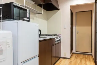 a kitchen with a white refrigerator and a wooden floor at \u96c0\u8272\u65b9\u5357 \u65b0\u5bbf\u99c5\u307e\u306714\u5206 \u6771\u4eac\u99c5\u307e\u306730\u5206 \u65b9\u5357\u753a\u5f92\u6b698\u5206 \u5bdd\u5ba4\u4e8c\u3064 \u6700\u59274\u4eba \u6d17\u6fef\u6a5f \u30ad\u30c3\u30c1\u30f3 \u96fb\u5b50\u30ec\u30f3\u30b8 in Tokyo