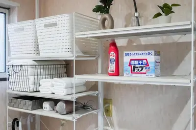 a shelf in a bathroom with towels and a bottle of cleaner at \u96c0\u8272\u65b9\u5357 \u65b0\u5bbf\u99c5\u307e\u306714\u5206 \u6771\u4eac\u99c5\u307e\u306730\u5206 \u65b9\u5357\u753a\u5f92\u6b698\u5206 \u5bdd\u5ba4\u4e8c\u3064 \u6700\u59274\u4eba \u6d17\u6fef\u6a5f \u30ad\u30c3\u30c1\u30f3 \u96fb\u5b50\u30ec\u30f3\u30b8 in Tokyo