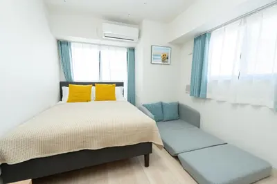 a small bedroom with a bed and two seats at KINSHICHO Tokyo Holiday Hotel in Tokyo