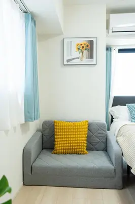 a gray couch with a yellow pillow in a bedroom at KINSHICHO Tokyo Holiday Hotel in Tokyo
