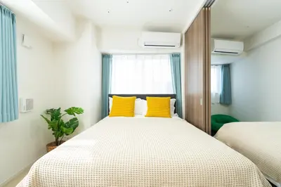 a bedroom with two beds with yellow pillows at KINSHICHO Tokyo Holiday Hotel in Tokyo