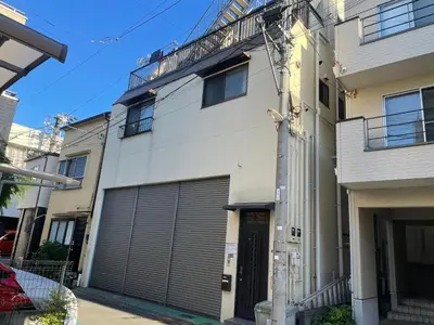 a white building with two garage doors on it at Homestay at M's House Not entire property just one room in Tokyo