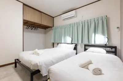 a bedroom with two beds with white sheets at M-stay Nishi-shinjuku in Tokyo