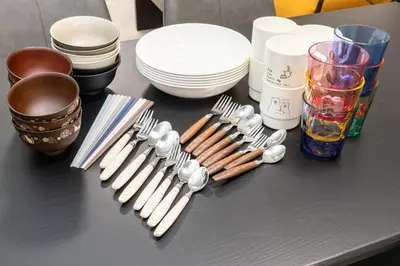 a table with forks and spoons and plates and utensils at M-stay Nishi-shinjuku in Tokyo