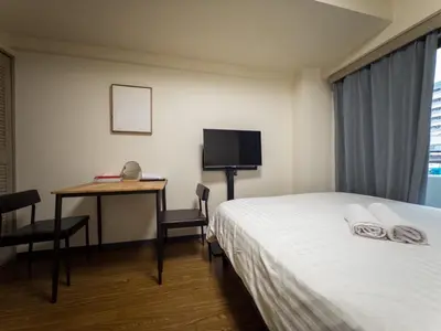 a hotel room with a bed and a desk and a television at Ichigaya Stay & Wi-Fi 1 in Tokyo