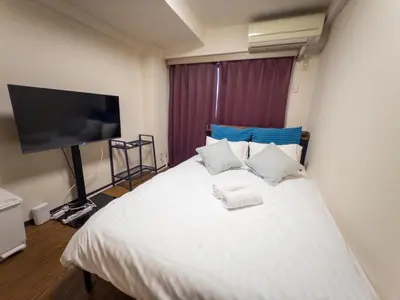 a bedroom with a white bed with a flat screen tv at Ichigaya Stay & Wi-Fi 1 in Tokyo