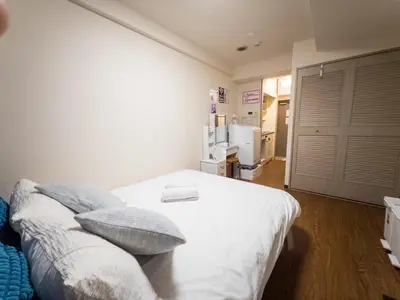 a bedroom with a white bed with pillows and a refrigerator at Ichigaya Stay & Wi-Fi 1 in Tokyo
