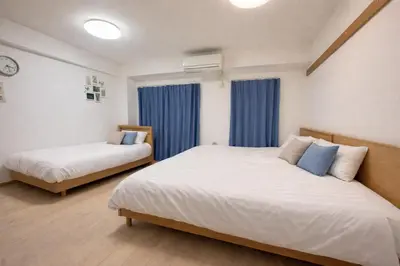 a bedroom with two beds and a window with blue curtains at YMK Oshiage 4B in Tokyo
