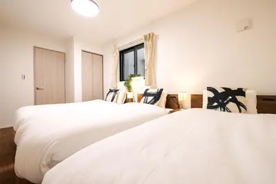 two beds in a room with chairs and a window at AS\u685c\u4e0a\u6c34Villa in Tokyo