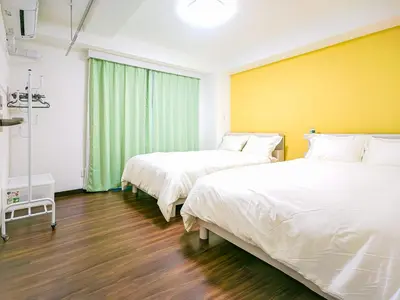 two beds in a room with yellow walls and wooden floors at YayoiHotel in Tokyo