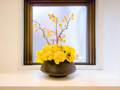 a vase filled with yellow flowers on a window sill at YayoiHotel in Tokyo