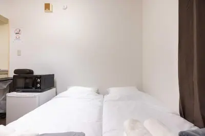 two beds in a room with white sheets and a tv at Ikebukuro-Mejiro Good Place House in Tokyo