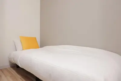 a white bed in a room with a yellow pillow at CH RESiDENCE \u4e21\u56fd in Tokyo