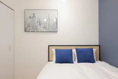a bedroom with a bed with two blue pillows at CH RESiDENCE \u4e21\u56fd in Tokyo